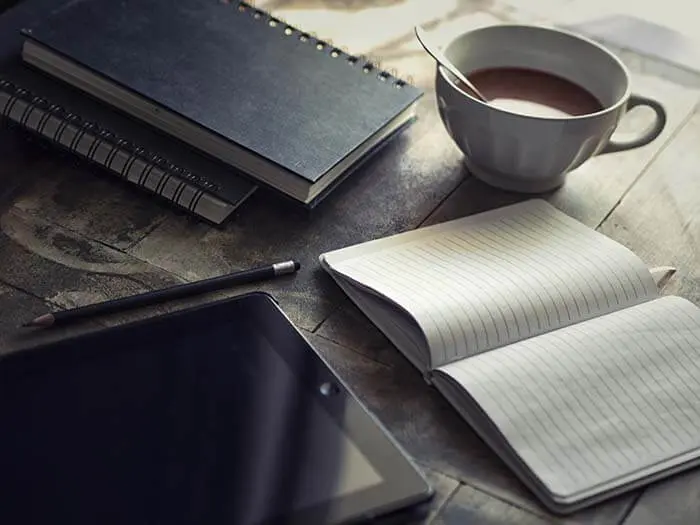 cup of coffee between notebooks